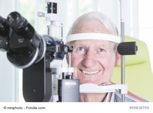 Portrait älterer Patient bei der Spaltlampenuntersuchung in einer Augenarztpraxis